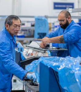 Two people in blue lab coats assemble Evolv Express walkthrough security systems.