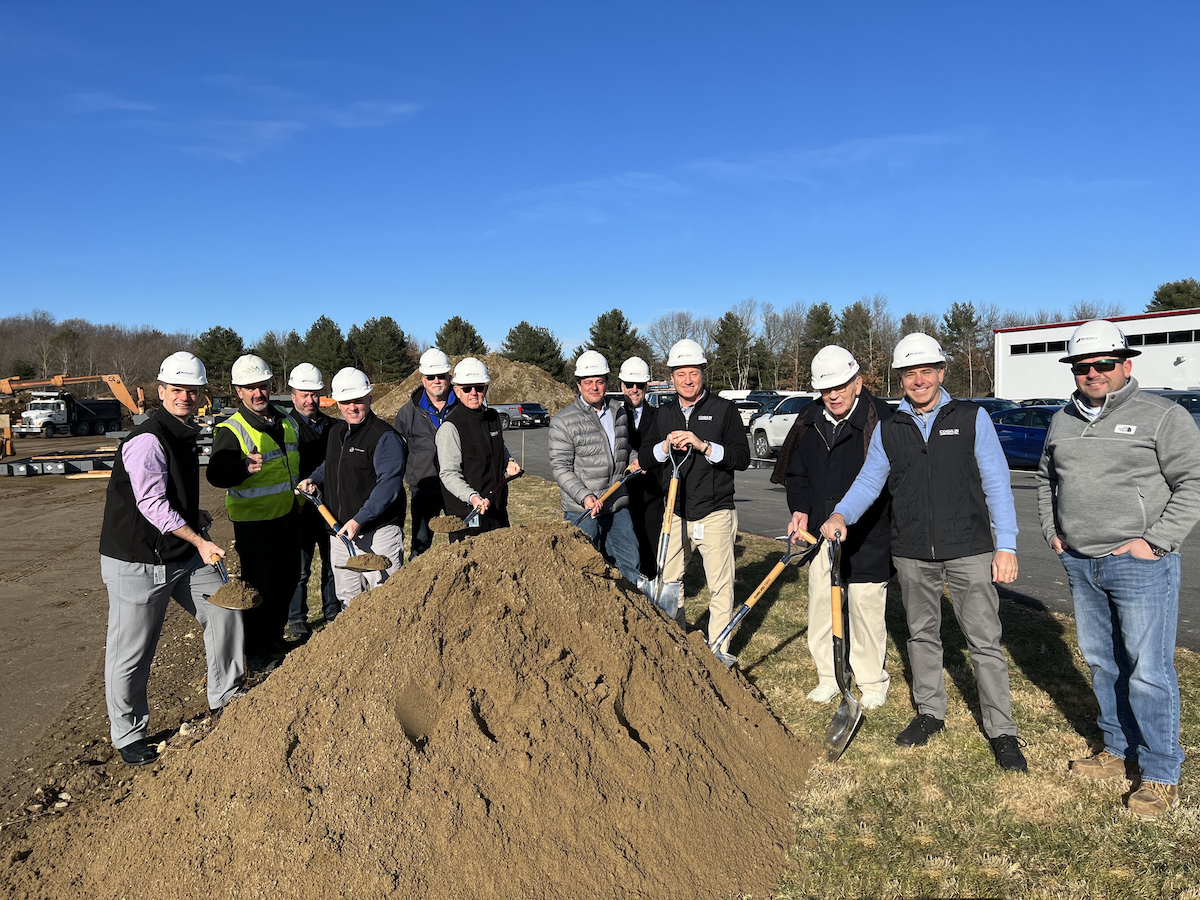 Cogmedix leadership wearing PPE, standing by a large pile of dirt and holding shovels, at the groundbreaking ceremony for the new medical engineering and manufacturing facility.