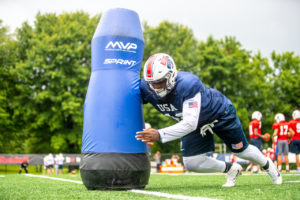 a football player tackles a blue MVP Sprint dummy manufactured by Columbia Tech