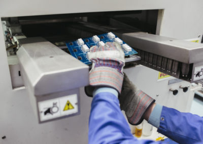 A freshly soldered printed circuit board is removed from the wave solder machine